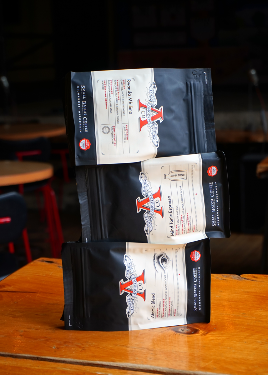 Three coffee bags with visible branding on a wooden surface